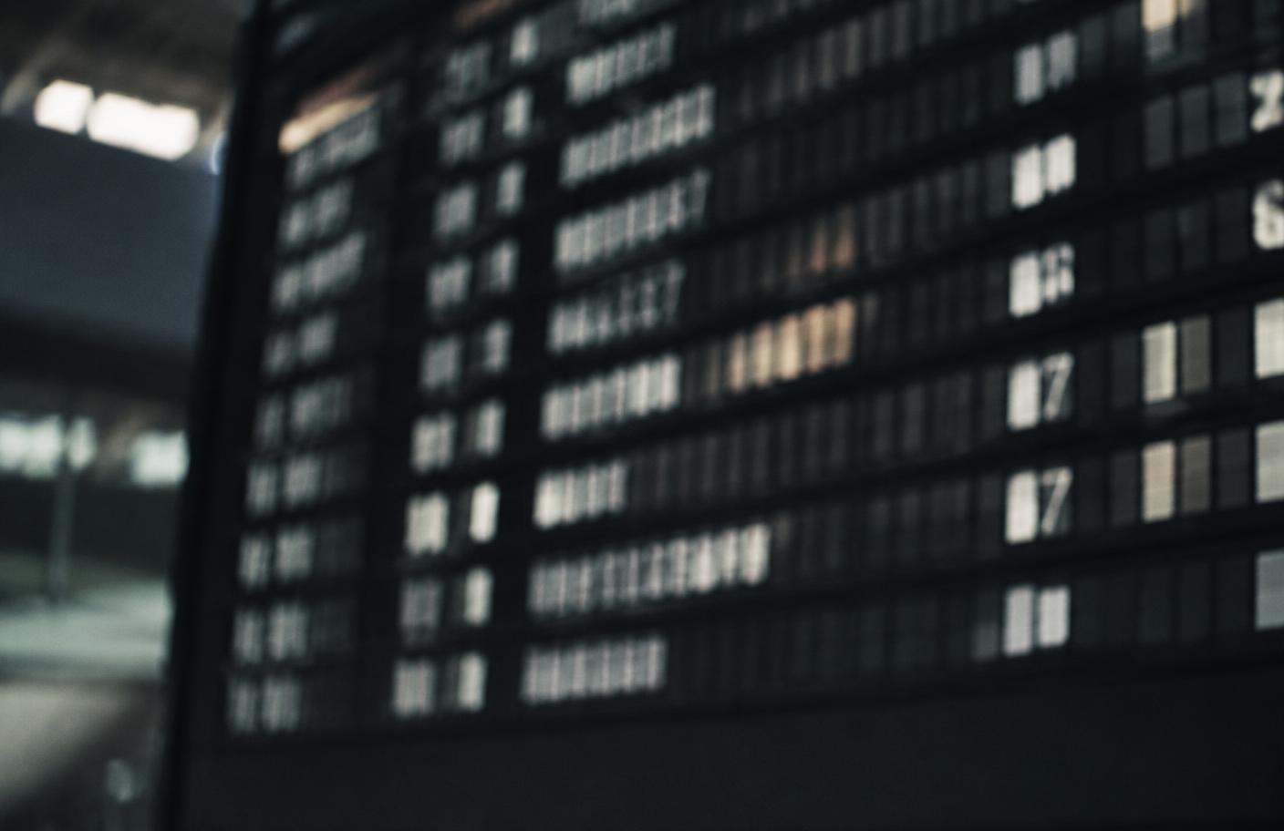 A split-flap airport departure board mid-flip, photographed out of focus.